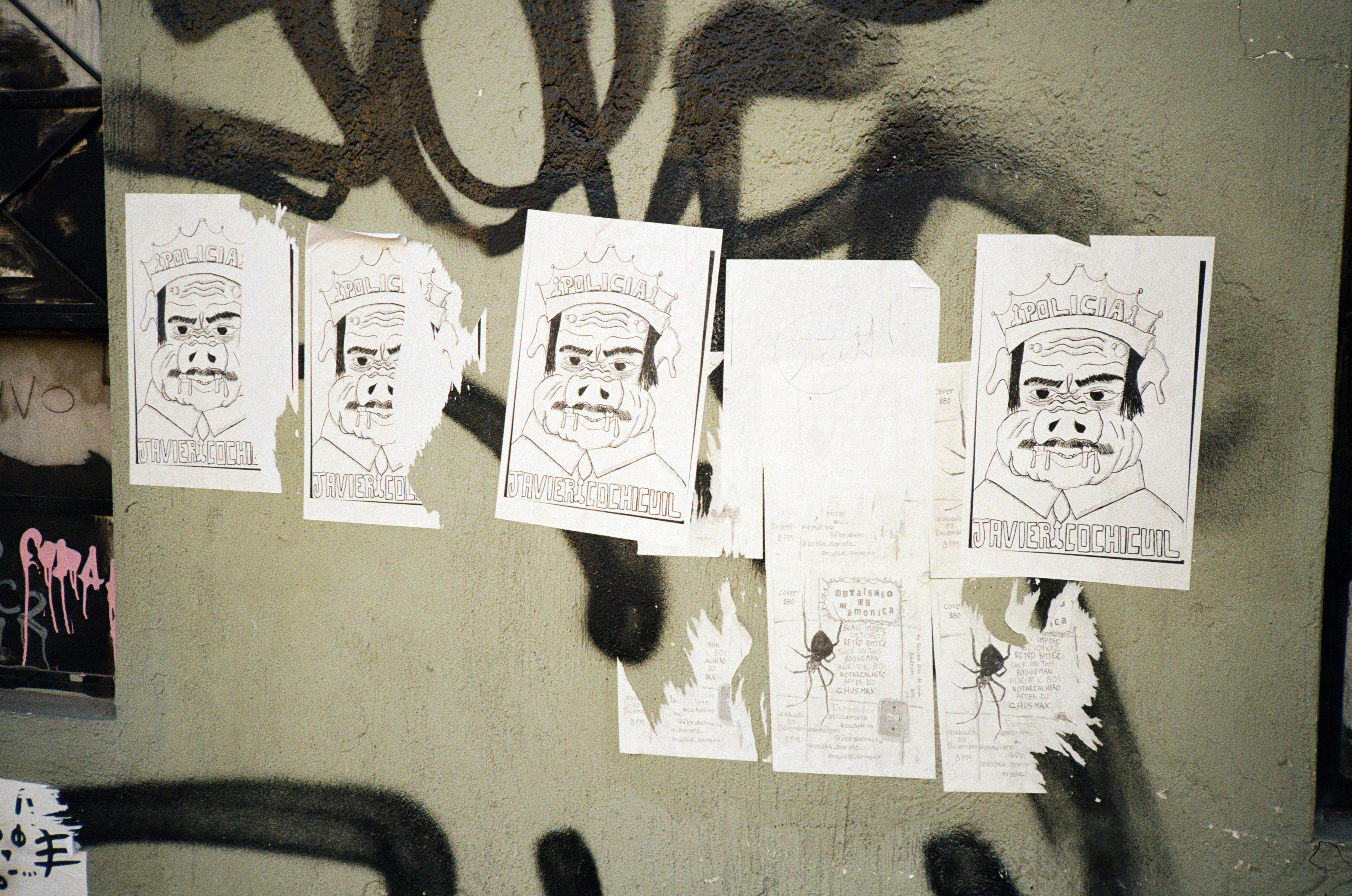 WHEAT PASTED POSTERS WITH AN ILLUSTRATION OF A COP AS A DROOLING SWEATING PUTRID PIG AND LETTERING AT THE BOTTOM THAT READS JAVIER COCHICUIL