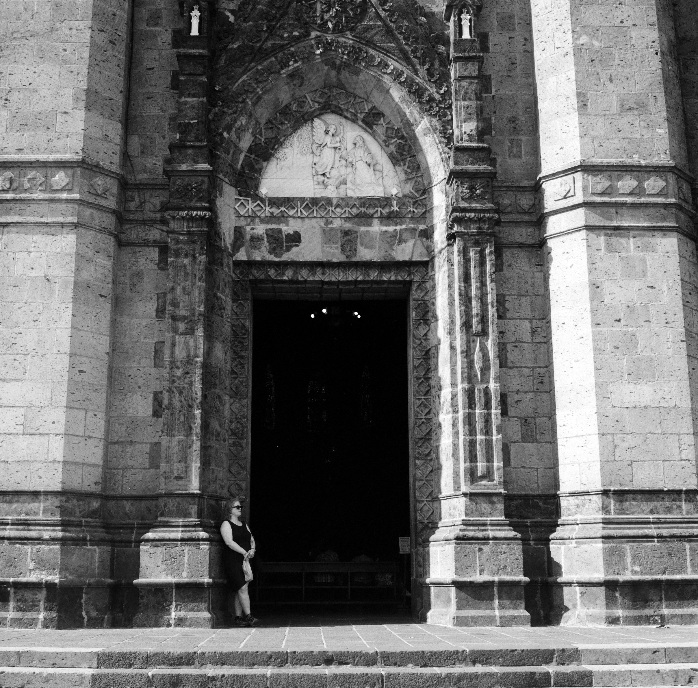 A WOMAN STANDING IN THE DOORWAY OF A CATHEDRAL IN GUADALAJARA