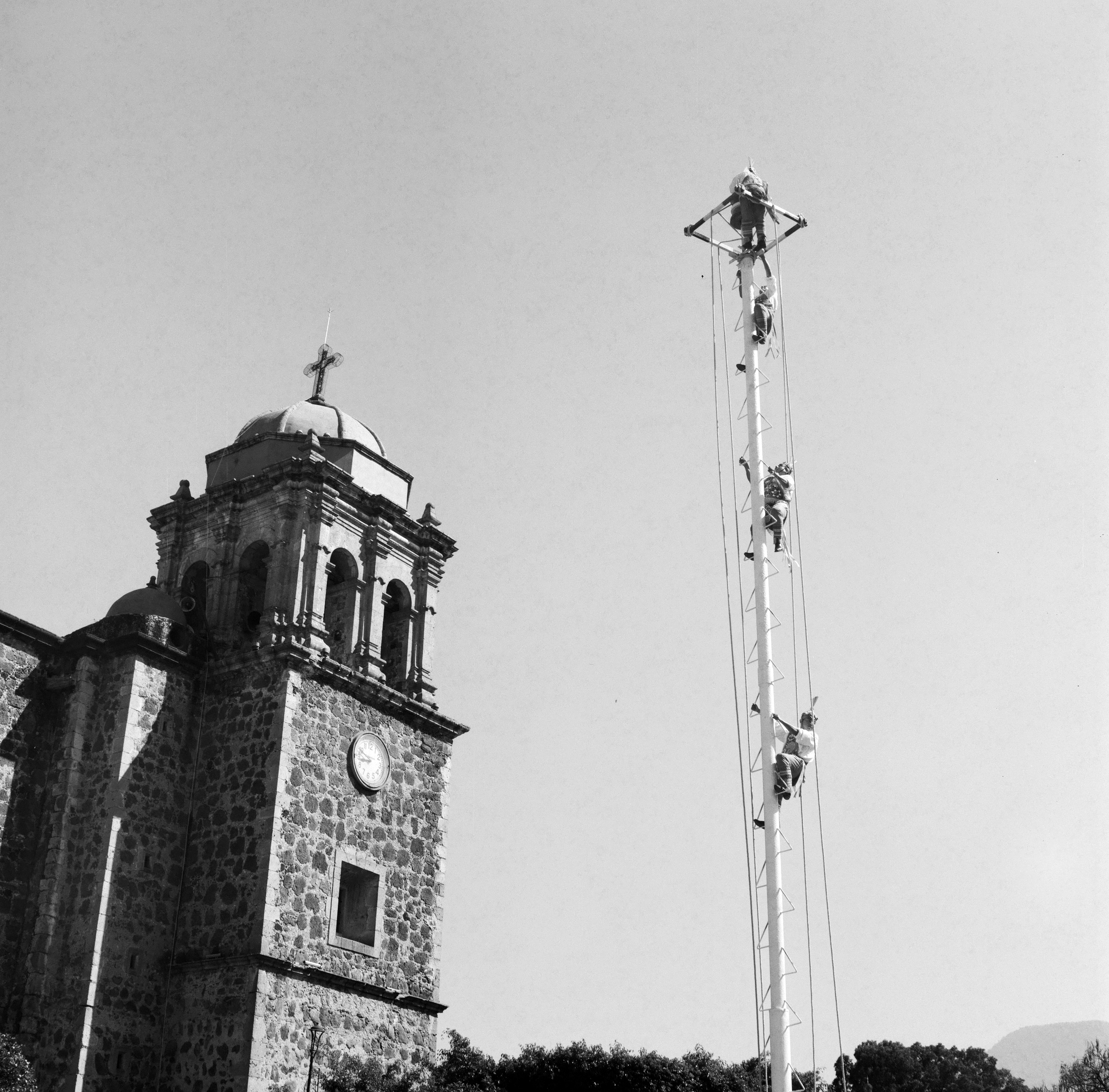 MEN CLIMB A TALL POLE IN PREPARATION FOR LA DANZA DE LOS VOLADORES