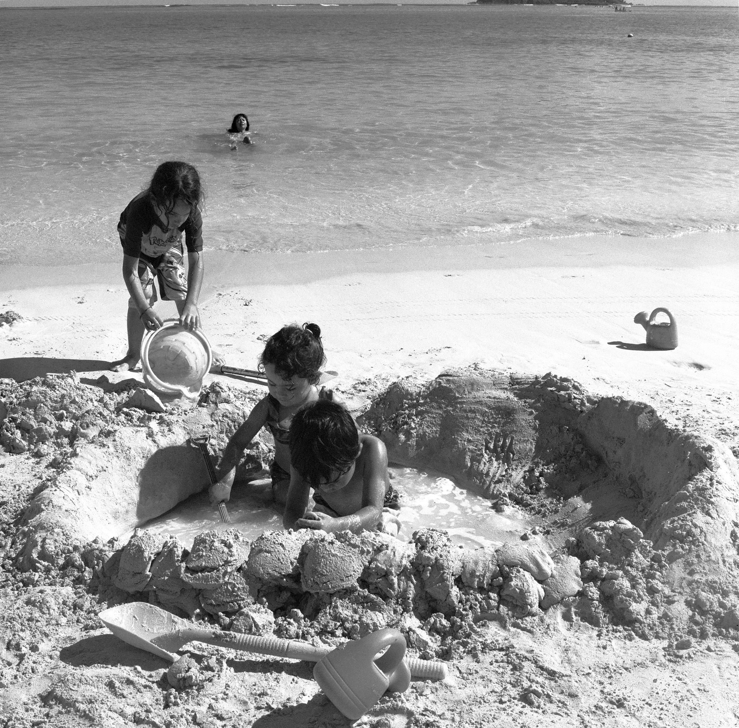 SONNY, LILA, AND MICAH WORK HARD ON BUILDING A SAND CIRCLE WITH THE OCEAN RIGHT BEHIND THEM