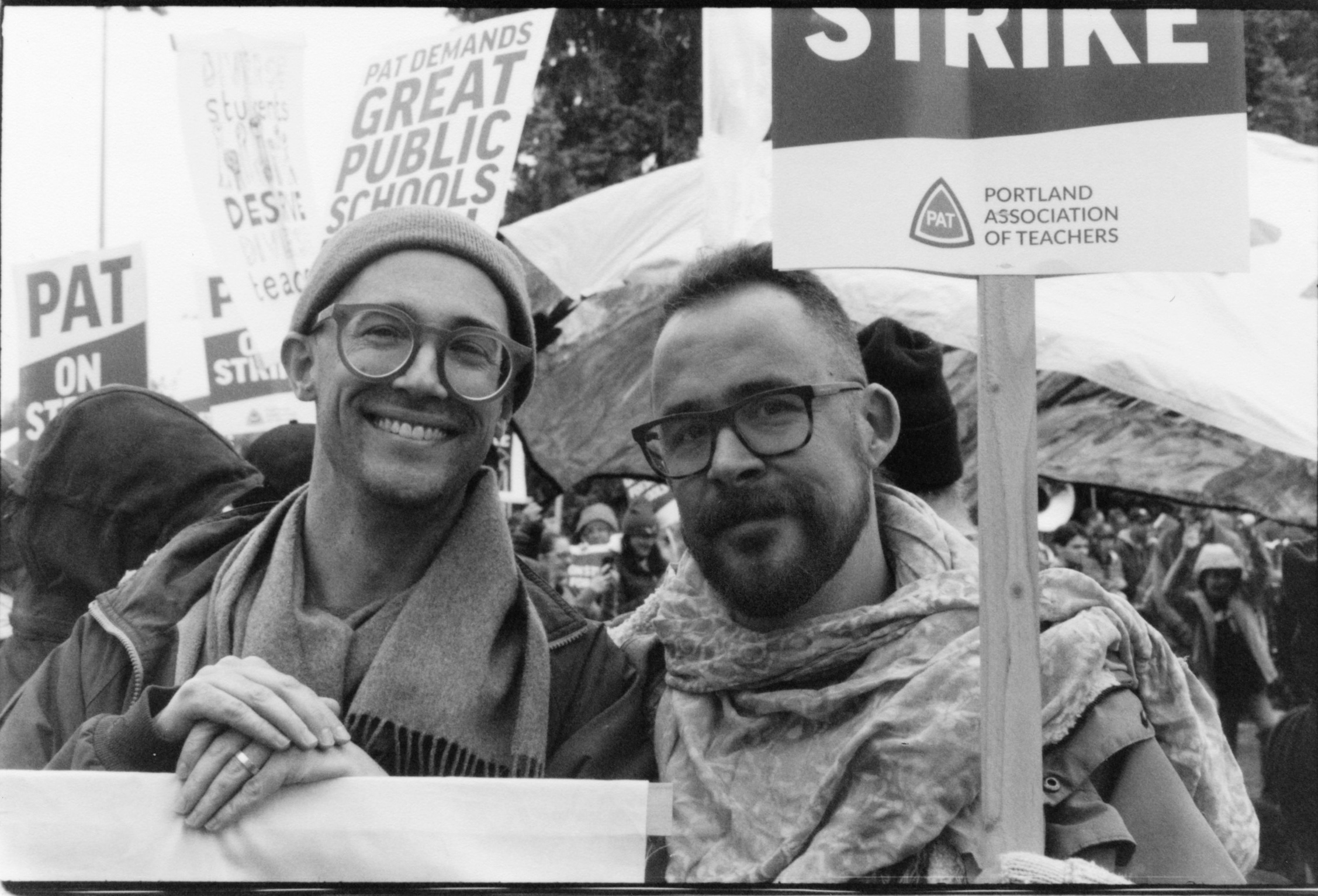 BLACK AND WHITE PORTRAIT OF TWO MEN WITH GLASSES HOLDING PICKET SIGNS