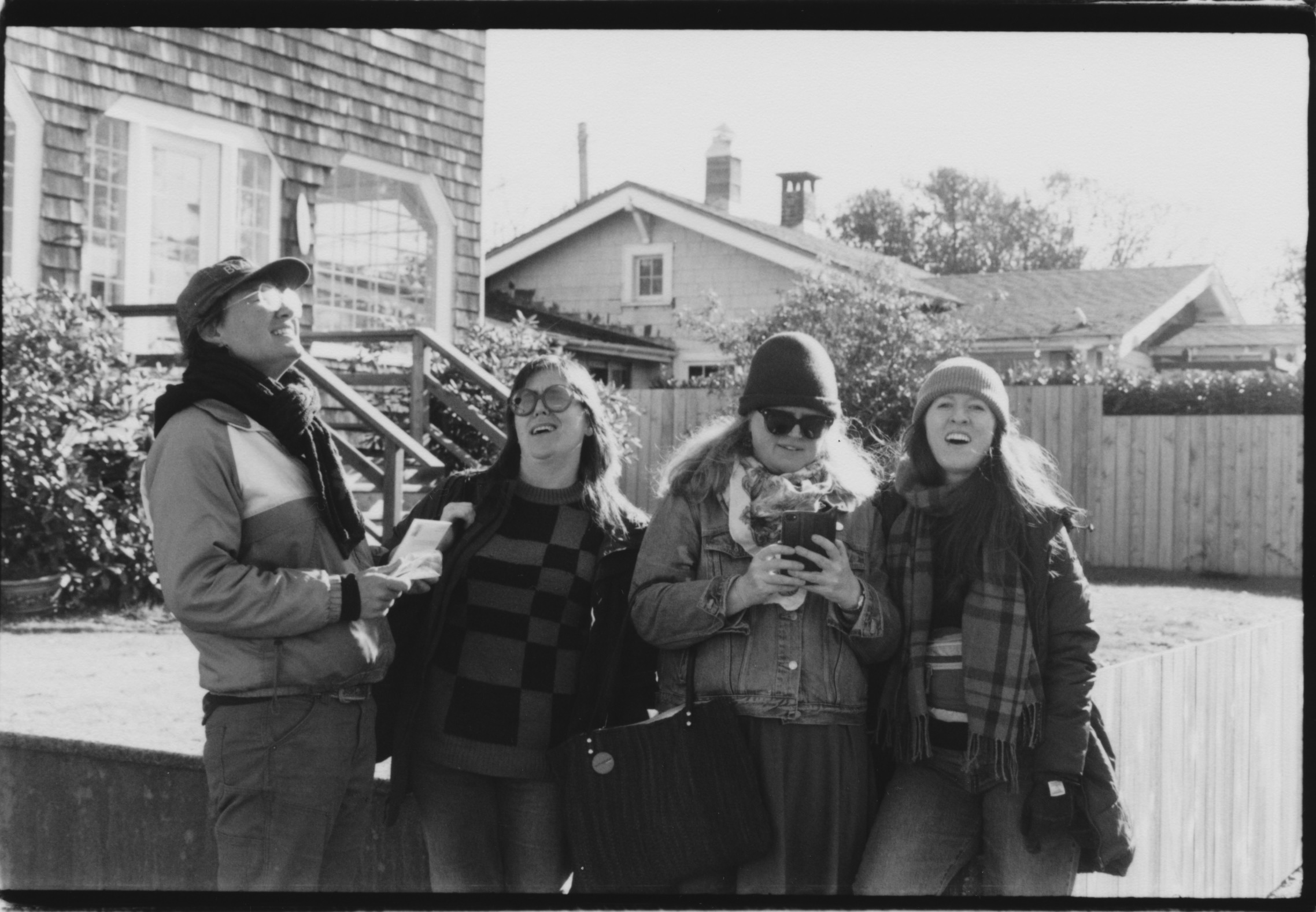 4 WOMEN STANDING IN FRONT OF A RENTAL VACATION HOUSE LOOKING IN DIFFERENT DIRECTIONS