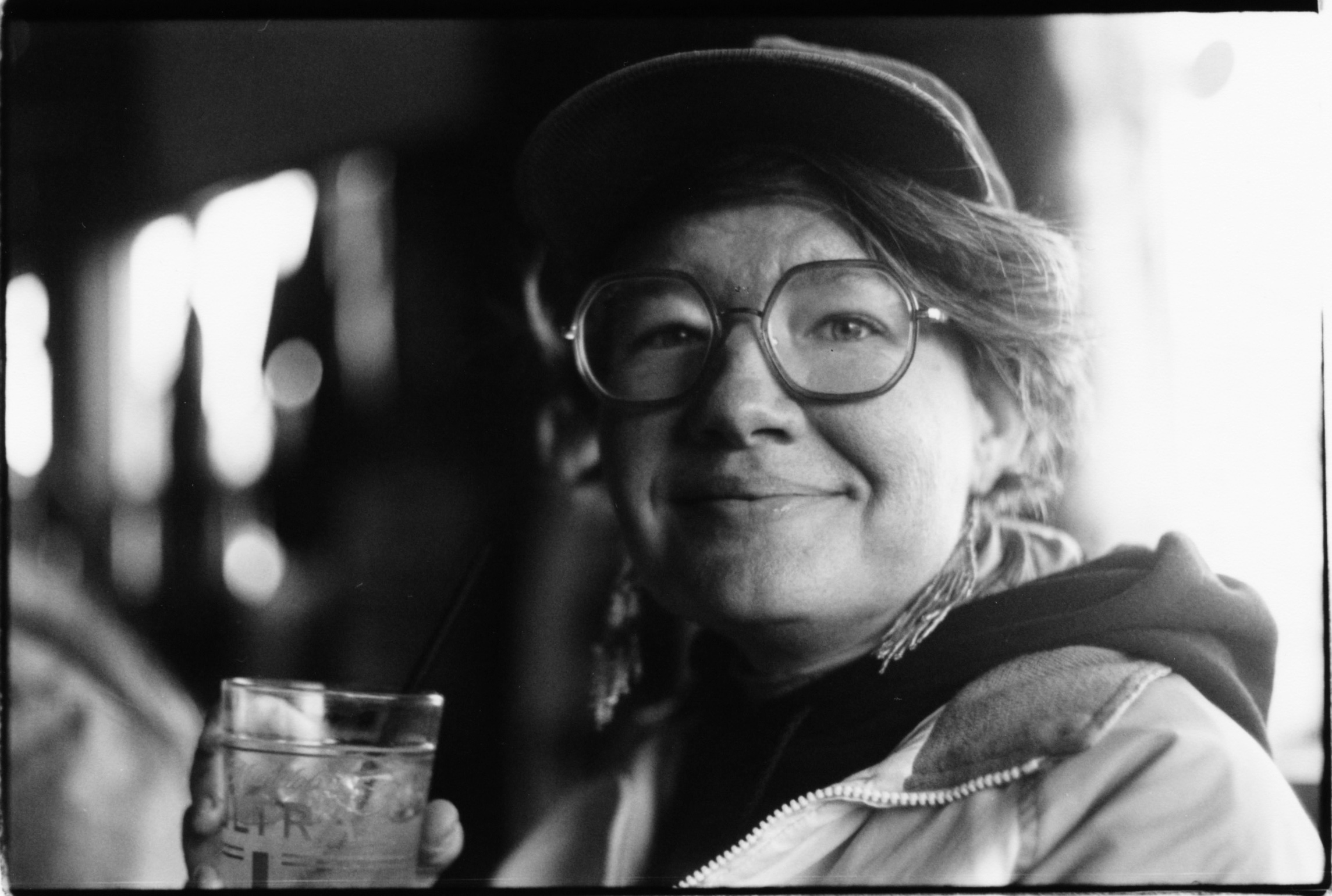A BLACK AND WHITE PORTRAIT OF A WHITE LESBIAN WITH HER DRINK IN A BAR