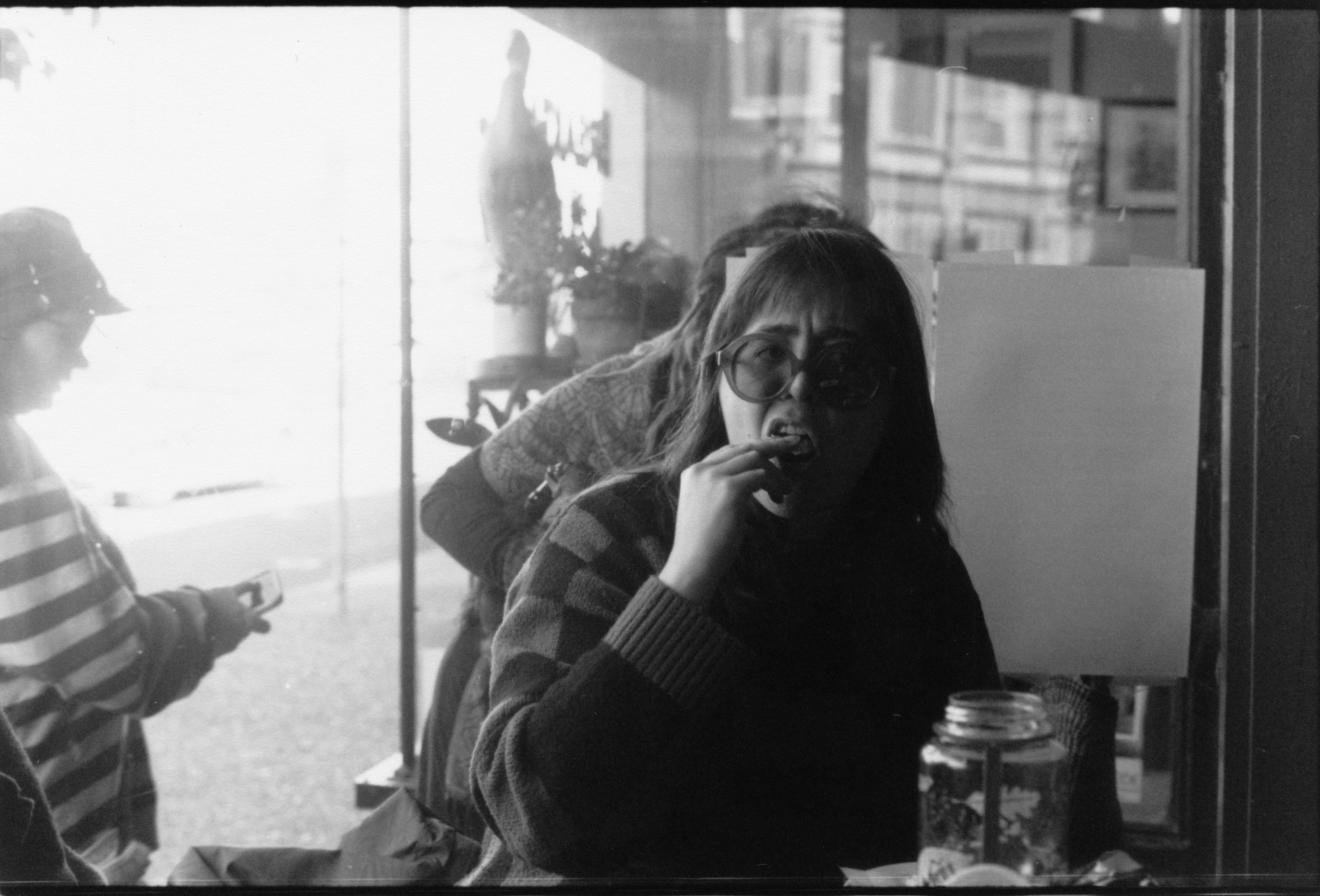A BLACK AND WHITE PORTRAIT OF A WOMAN BITING INTO A BREAKFAST ITEM IN A BEACH COFFEE SHOP
