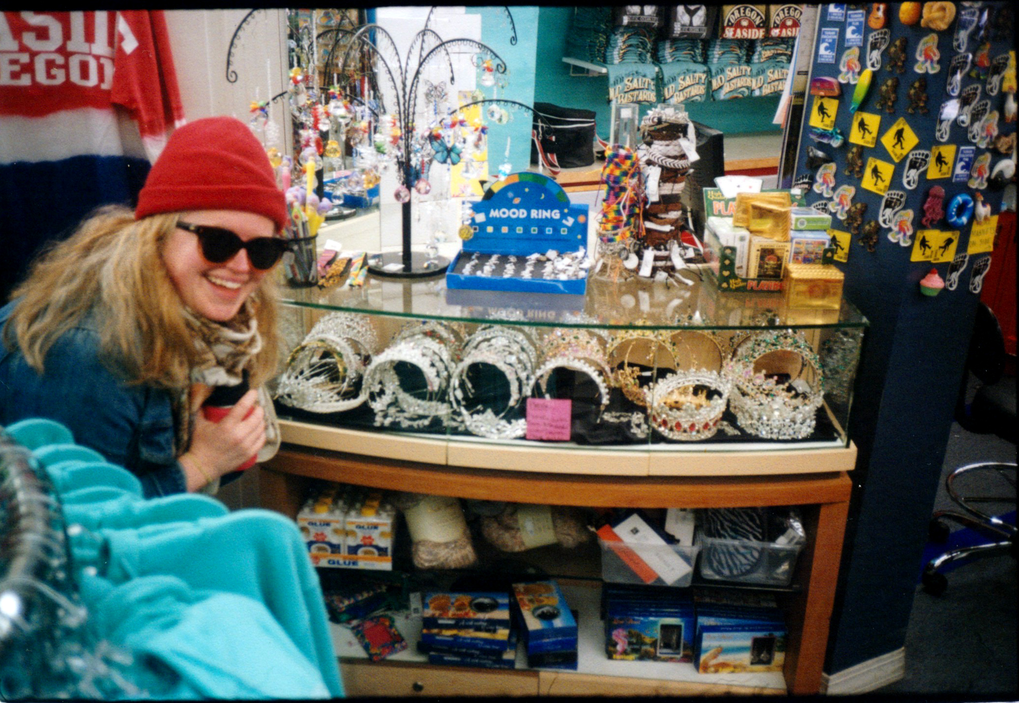A WOMAN POSES IN A BEACH GIFTSHOP NEXT TO A GLASS CASE FULL OF TIARAS