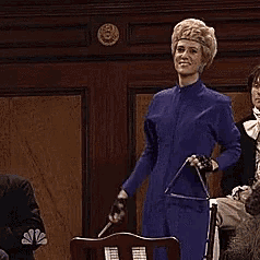 kristen wiig kicks her leg while holding a triangle